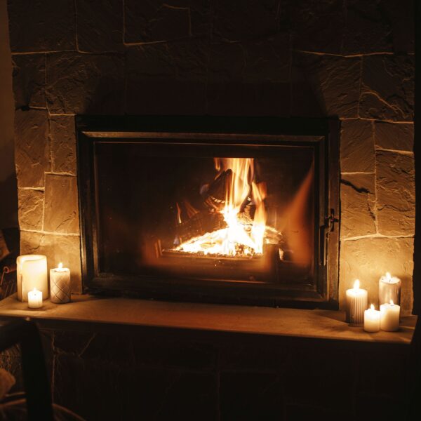 Cozy burning fireplace and candles in dark evening room. Firepla