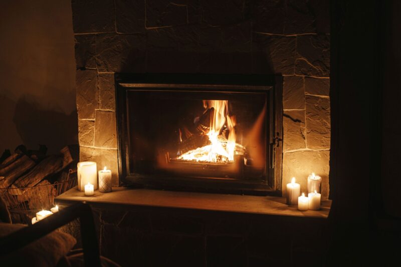 Cozy burning fireplace and candles in dark evening room. Firepla